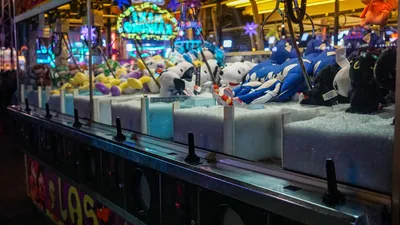 A brightly lit arcade claw machine packed with coloured prizes.