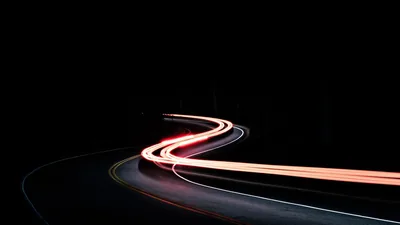 A single ribbon of tail-light trailing away down an empty road.