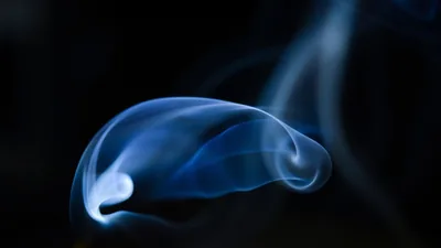 Cold blue smoke drifting in front of a black backdrop.