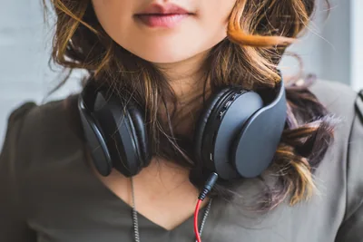 A person wearing over-ear headphones, eyes closed, listening.