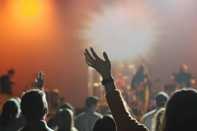 A stage lighting rig throwing beams over a live audience.