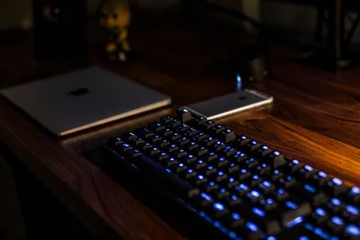 A backlit keyboard photographed in low light, blue glow under the keycaps.