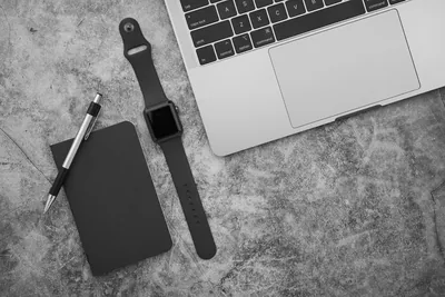 An overhead view of a tidy desk with a laptop and a notebook.